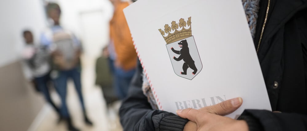 Eine Frau hält im Bürgeramt im Landesamt für Einwanderung (LEA) ihre Einbürgerungsurkunde in der Hand. 