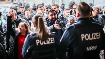 Aufgebrachte Kunden diskutieren vor der Sparkassenfiliale in Buer mit Polizeibeamten nach der Räumung des Vorraums der Filiale.