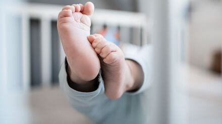 Die Füße eines Babys sind in einem Kinderbett zu sehen.