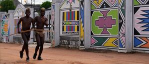 Junge Männer vom Volk der Ndebele laufen am Haus von Esther Mahlangu, einer zeitgenössischen südafrikanischen Künstlerin, in KwaMhlanga in Mpumalanga, Südafrika, vorbei.