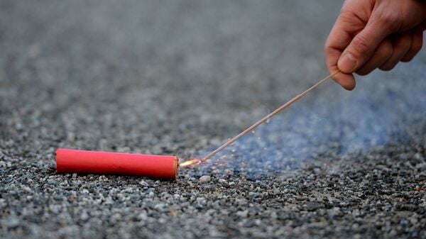 Der Bildausschnitt zeigt eine Hand, die einen Böller anzündet.