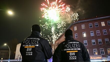 Zwischen Party und Großeinsatz: Polizisten aus Baden-Württemberg beobachten am Rande der Böllerverbotszone Sonnenallee das Feuerwerk.