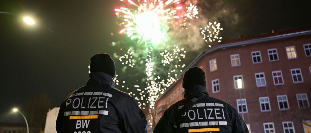 Zwischen Party und Großeinsatz: Polizisten aus Baden-Württemberg beobachten am Rande der Böllerverbotszone Sonnenallee das Feuerwerk.