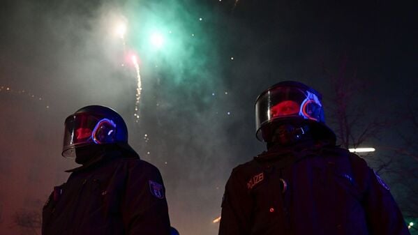 Feuerwerk explodiert während der Silvesternacht in Neukölln hinter Polizei in Berlin.