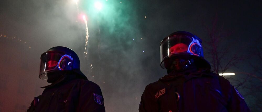 Feuerwerk explodiert während der Silvesternacht in Neukölln hinter Polizei in Berlin.