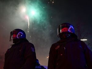 Feuerwerk explodiert während der Silvesternacht in Neukölln hinter Polizei in Berlin.