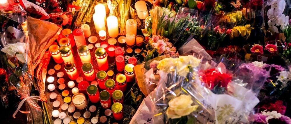 Ein Blumen- und Kerzenmeer erinnert an Tote und Verletzte in der Nähe des Brandortes. 