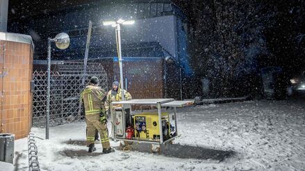 03.01.2026, Berlin: Einsatzkräfte der Berliner Feuerwehr stehen vor einem Generator-Lichtmast an einer Katastrophenschutz-Kontraktstelle vor der Carl-Schuhmann-Sportanlage im Stadtteil Lichterfelde während eines Stromausfalls. Nach dem Brand einer Kabelbrücke ist im Südwesten Berlins für 50.000 Haushalte und 2.000 Gewerbebetriebe der Strom ausgefallen. Foto: Carsten Koall/dpa +++ dpa-Bildfunk +++