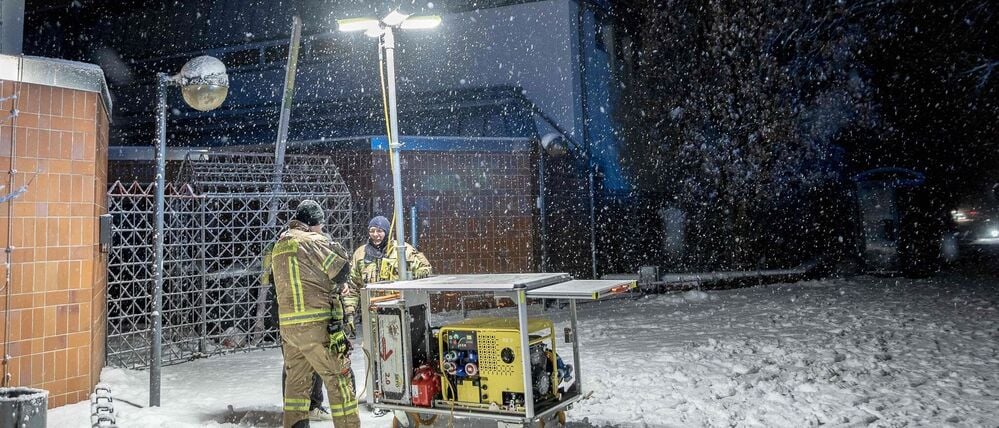 03.01.2026, Berlin: Einsatzkräfte der Berliner Feuerwehr stehen vor einem Generator-Lichtmast an einer Katastrophenschutz-Kontraktstelle vor der Carl-Schuhmann-Sportanlage im Stadtteil Lichterfelde während eines Stromausfalls. Nach dem Brand einer Kabelbrücke ist im Südwesten Berlins für 50.000 Haushalte und 2.000 Gewerbebetriebe der Strom ausgefallen. Foto: Carsten Koall/dpa +++ dpa-Bildfunk +++