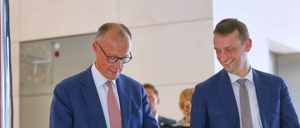 CDU-Chef Friedrich Merz kommt aus der SPD-Fraktionssitzung und freut sich mit seinem Stabschef Jacob Schrot über sein Namensschild mit SPD-Logo, das er mitgenommen hat (Archivbild).