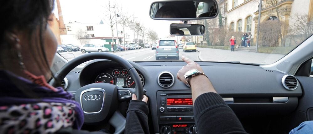 Eine 17-jährige Fahrschülerin und ihr Fahrlehrer sitzen in einem Fahrschulauto.