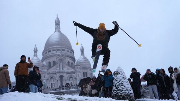 Im Pariser Viertel Montmartre: Ein Mann springt mit seinen Skiern den Hügel bei der Basilika Sacre-Coeur hinunter.