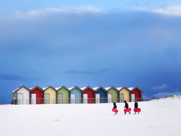 05.01.2026, Großbritannien, Blyth: Menschen genießen die winterlichen Bedingungen vor bunten Strandhütten. Foto: Owen Humphreys/PA Wire/dpa +++ dpa-Bildfunk +++
EU_Snow