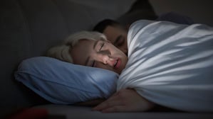 Ein junges Paar liegt im Bett (Symbolbild).