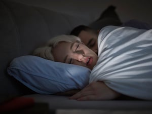 Ein junges Paar liegt im Bett (Symbolbild).