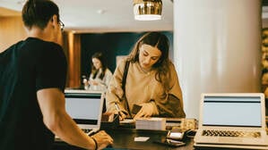 Eine junge Frau an der Hotel Rezeption beim Hotel Check-in (Symbolbild).