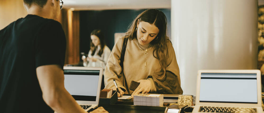 Eine junge Frau an der Hotel Rezeption beim Hotel Check-in (Symbolbild).