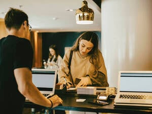 Eine junge Frau an der Hotel Rezeption beim Hotel Check-in (Symbolbild).