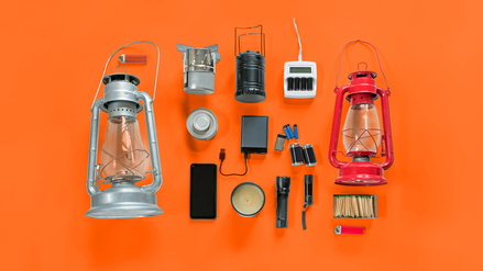 Überlebensausrüstung für den Fall eines Stromausfalls, einschließlich Petroleumlampen, Taschenlampen, Batterien, Ladegerät und externer Stromspeicher.