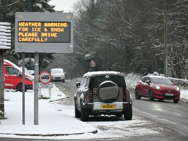 Motorists pass a sign cautioning drivers about the snowy conditions in the town of Glossop, Derbyshire, northern England on January 6, 2026, after a light snow covered the region overnight. The UK's Met Office issued fresh weather warnings for January 5-6 for snow and ice for Scotland, Northern Ireland and parts of northern England and said cold weather health alerts for all English regions would remain in place until January 9. (Photo by Oli SCARFF / AFP)