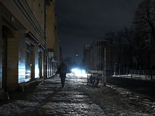 dpatopbilder - 06.01.2026, Berlin: Eine Person läuft eine dunkle Straße in Zehlendorf entlang, die nur durch einen Autoscheinwerfer erhellt wird. Zehntausende Menschen im Südwesten der Hauptstadt haben keinen Strom - und das bei Schnee und Kälte. Foto: Elisa Schu/dpa +++ dpa-Bildfunk +++