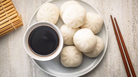 Xiao Long Bao. Chinesische Teigtaschen auf dem Teller und Sojasauce auf dem Küchentisch. Xiao Long Bao.