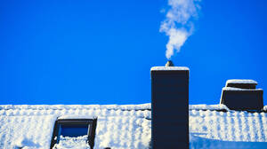 Rauchender Schornstein eines Wohnhauses im Winter (Symbolbild)