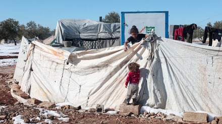 A girl helps her sister in front of their tents in the Aleppo countryside, after days of snowstorm that occurred in northern Syria, Aleppo, Syria, January 5, 2026. REUTERS/Mahmoud Hassano     TPX IMAGES OF THE DAY     