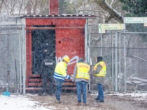 Einsatzkräfte der Polizei stehen an der Brandstelle einer Kabelbrücke vor dem Kraftwerk Lichterfelde am Teltowkanal.