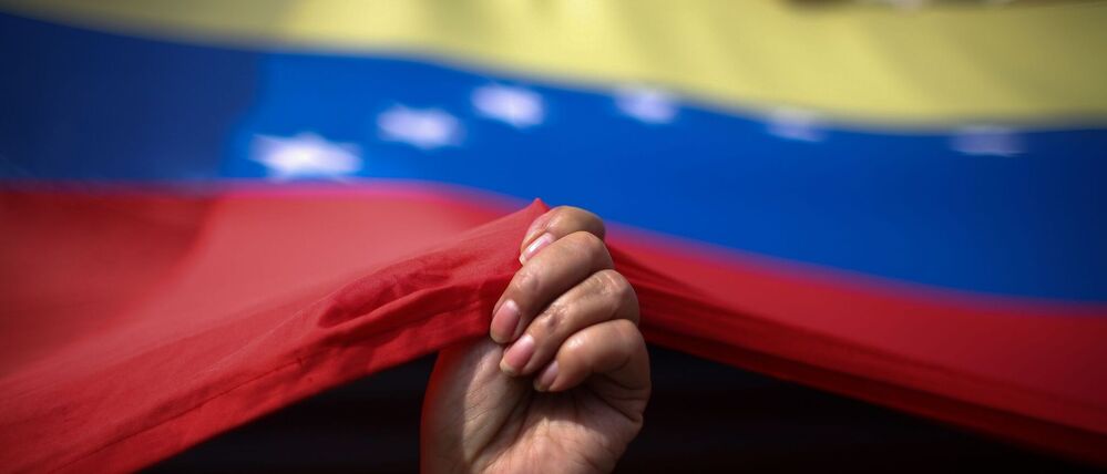 Eine Frau hält eine Fahne von Venezuela (Symbolfoto).