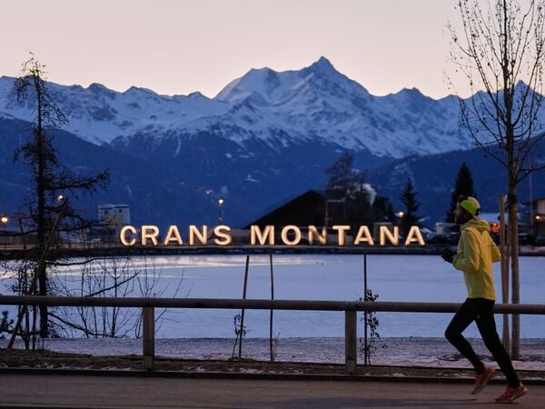 03.01.2026, Schweiz, Crans-Montana: Ein Mann läuft am frühen Morgen in Crans-Montana in den Schweizer Alpen. In dem Ort hatte ein verheerendes Feuer in einer Bar während der Silvesterfeierlichkeiten Tote und Verletzte gefordert. Foto: Baz Ratner/AP/dpa +++ dpa-Bildfunk +++