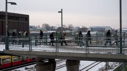 Menschen gehen über eine Brücke in der Nähe vom Bahnhof Warschauer Straße. 