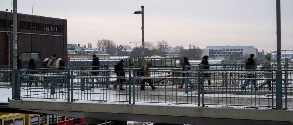 Menschen gehen über eine Brücke in der Nähe vom Bahnhof Warschauer Straße. 