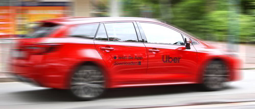 Ein Fahrzeug mit der Werbung von Uber fährt auf einer Straße.