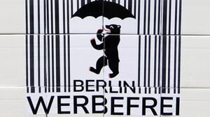 Ein Logo des Volksbegehrens „Berlin Werbefrei“ mit einem Strichcode und einem Berliner Bären mit Regenschirm.