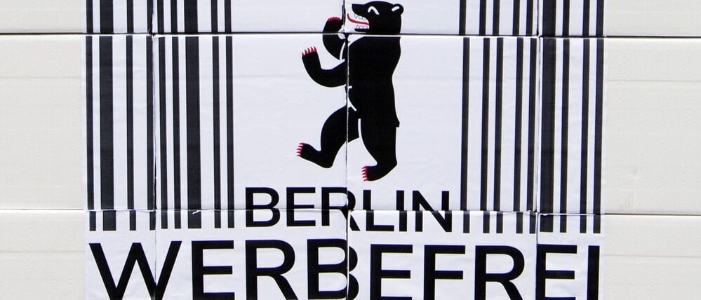 Ein Logo des Volksbegehrens „Berlin Werbefrei“ mit einem Strichcode und einem Berliner Bären mit Regenschirm.