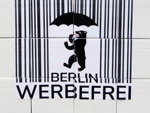 Ein Logo des Volksbegehrens „Berlin Werbefrei“ mit einem Strichcode und einem Berliner Bären mit Regenschirm.