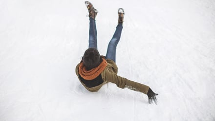 Eine junge Frau rutscht einen vereisten Hang hinunter (Symbolbild).