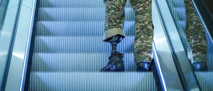Ein Mann in ukrainischer Uniform steht mit einer Prothese auf der Rolltreppe bei der Internationalen Konferenz zum Wiederaufbau der Ukraine in Berlin. Die internationale Wiederaufbaukonferenz für die Ukraine findet in Berlin am 11. und 12. Juni statt. +++ dpa-Bildfunk +++