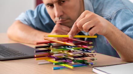 Close-up of the hand of a bored lazy worker with his hands wasting time playing with pens sitting at a desk in the office