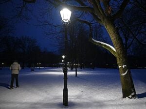 Ein Mann geht im Berliner Volkspark Friedrichshain einen beleuchteten Weg entlang.