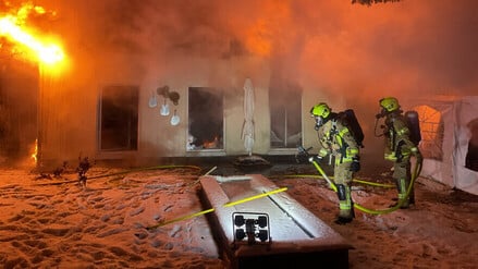Einsatzkräfte der Berliner Feuerwehr bei den Löscharbeiten vor einer brennenden Lagerhalle in Neukölln.