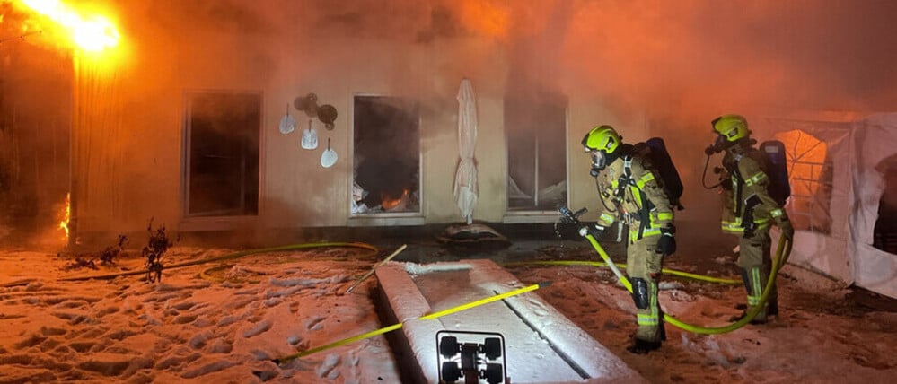 Einsatzkräfte der Berliner Feuerwehr bei den Löscharbeiten vor einer brennenden Lagerhalle in Neukölln.