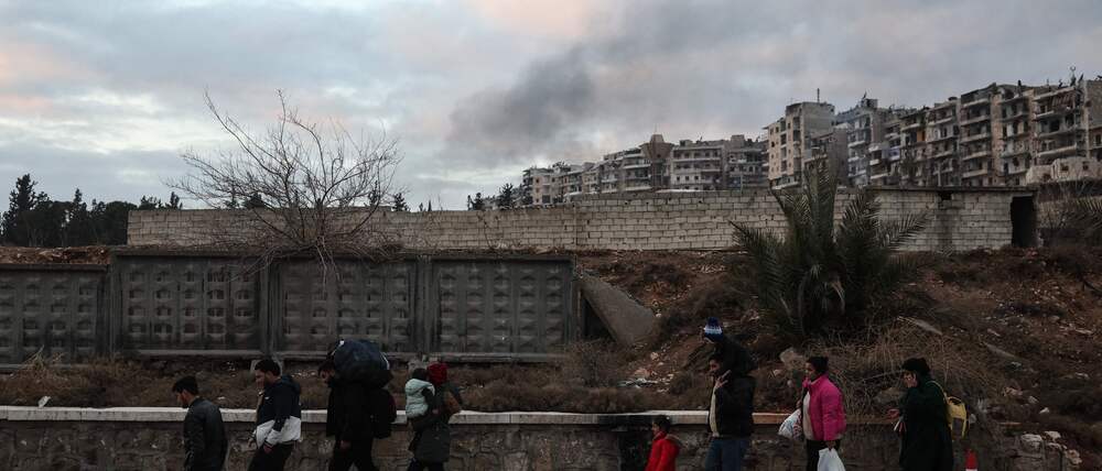 Residents carrying their belongings leave Aleppo's Kurdish-majority Sheikh Maqsud neighbourhood on January 10, 2026, after days of deadly clashes between Kurdish fighters and security forces. Syrian authorities on January 10 began transferring Kurdish fighters from Aleppo's Sheikh Maqsud neighbourhood to the country's northeast, state television reported. (Photo by OMAR HAJ KADOUR / AFP)
