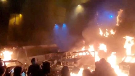 Protestierende in Teheran vor brennenden Fahrzeugen.