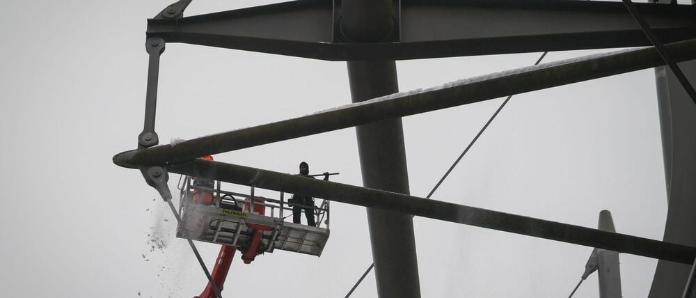 Arbeiter mit einem Hubsteiger entfernen Eis und Schnee von den Trägern des Stadiondachs am Volksparkstadion.