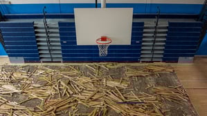 Removal of an old wooden plank gymnasium floor as part of a gym renovation project.