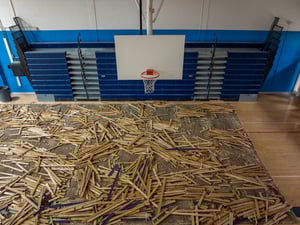 Removal of an old wooden plank gymnasium floor as part of a gym renovation project.