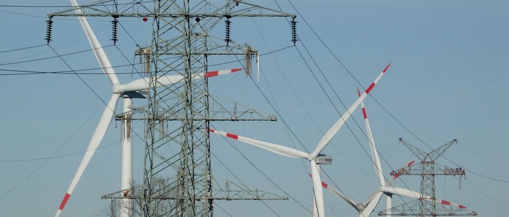 Windkraftanlagen und Strommasten - beides steht für den Ausbau erneuerbare Energie. (Symbolbild)