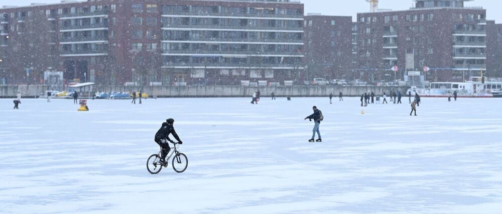 12.01.2026, Berlin: Ein Mann fährt auf der zugefrorenen Eisfläche der Rummelsberger Bucht Fahrrad. In der Nacht zu Montag sind überregional Glatteisregen bis hin zu Unwettergefahr möglich. Foto: Elisa Schu/dpa +++ dpa-Bildfunk +++